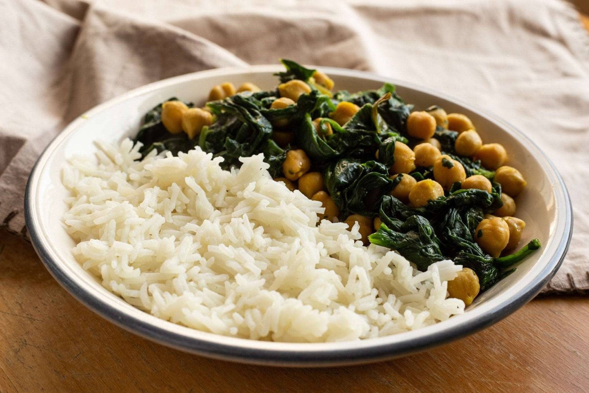 a close up of a bowl of basmati rice with spinach and chickpeas curry