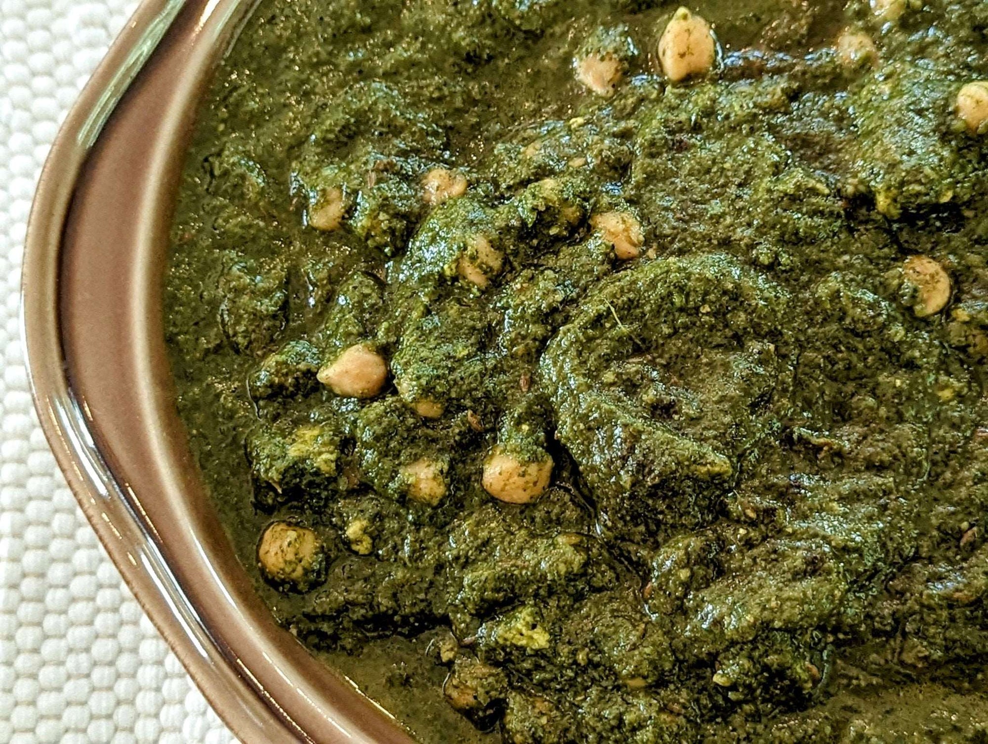 a close up of a bowl of chana saag, chickpeas with mixed pureed greens