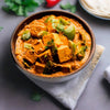 a close up of a bowl paneer curry food on a table with bell peppers in a rich and creamy onion and tomato curry sauce